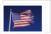 American Flag is blurred with the motion of the wind against the blue sky by Anonymous