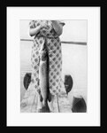 Woman holds on large Northern Pike on a lake pier, ca. 1950. by Anonymous