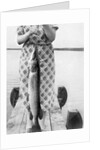 Woman holds on large Northern Pike on a lake pier, ca. 1950. by Anonymous