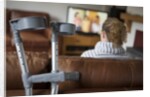 Woman watching TV with crutches by Anonymous