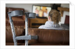 Woman watching TV with crutches by Anonymous