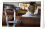 Woman watching TV with crutches by Anonymous