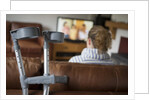Woman watching TV with crutches by Anonymous