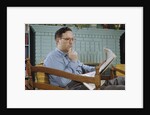 Pensive Man Reading Newspaper in Living Room by Anonymous