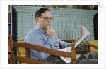 Pensive Man Reading Newspaper in Living Room by Anonymous