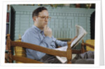 Pensive Man Reading Newspaper in Living Room by Anonymous