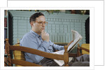 Pensive Man Reading Newspaper in Living Room by Anonymous