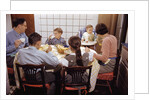 Family Eating Together at Dinner Table by Anonymous