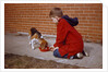 Boy Feeding Dog on Sidewalk by Anonymous