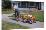 Boy Riding Tricycle and Towing Wagon by Anonymous