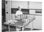 Man Taking Bread Loaves from Oven by Anonymous