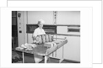 Man Taking Bread Loaves from Oven by Anonymous