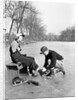 Man Putting on Woman's Ice Skates by Anonymous