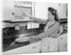 Woman Putting Dishes In Cabinet by Anonymous