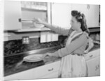Woman Putting Dishes In Cabinet by Anonymous