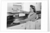 Woman Putting Dishes In Cabinet by Anonymous