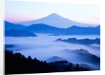 Distant view of Mount Fuji silhouetted against blue sky by Anonymous