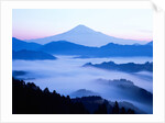 Distant view of Mount Fuji silhouetted against blue sky by Anonymous
