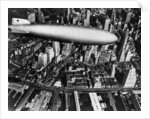 The German airship, the Hindenburg, above Manhattan, New York in 1936, on its way to its berth at Lakehurst , New Jersey, the same place where it inexplicably burst into flames the next year. by Anonymous