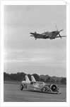Airplane Flying Over Race Car in Action by Anonymous