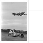 Airplane Flying Over Race Car in Action by Anonymous