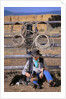 Cowboy and Dog Sitting Against Fence by Anonymous