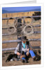 Cowboy and Dog Sitting Against Fence by Anonymous
