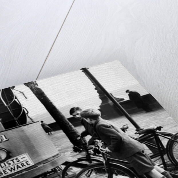 Boys on bicycles cross in front of a tram by Associated Newspapers