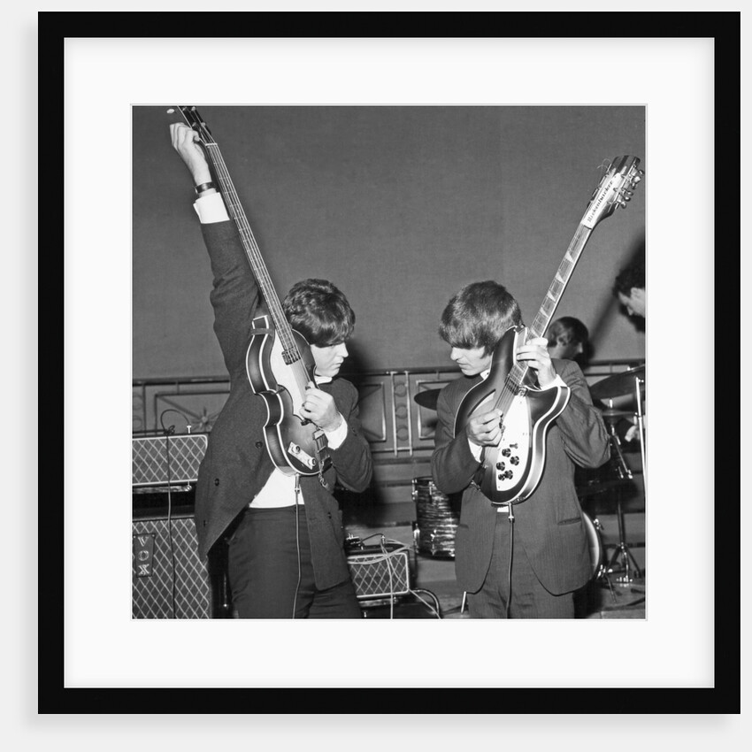 Paul McCartney and George Harrison tune their guitars by Associated Newspapers