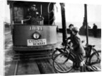 Boys on bicycles cross in front of a tram by Associated Newspapers