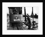 Boys on bicycles cross in front of a tram by Associated Newspapers