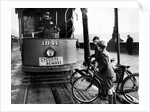 Boys on bicycles cross in front of a tram by Associated Newspapers