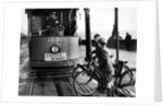 Boys on bicycles cross in front of a tram by Associated Newspapers