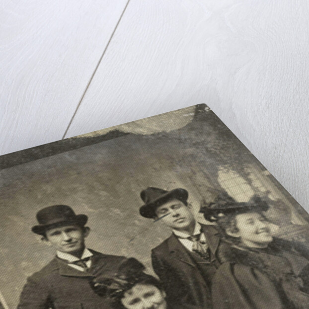 Portrait of two men and two women, one of whom looks away laughing, standing and sitting in front of a painted backdrop by Anonymous