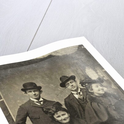 Portrait of two men and two women, one of whom looks away laughing, standing and sitting in front of a painted backdrop by Anonymous