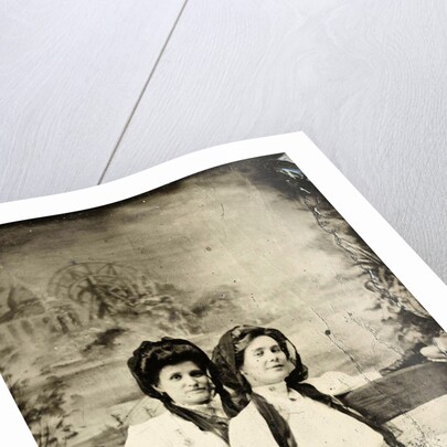 Portrait of two women sitting on a bench in front of a painted backdrop (chapel or church (?) In a lake), in the left part of the American flag by Anonymous