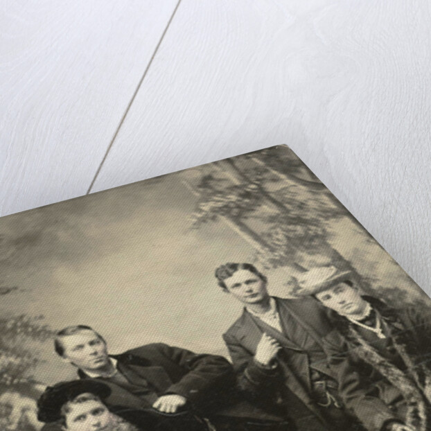 Two men and two women standing and sitting in front of a painted backdrop (forest) by Anonymous