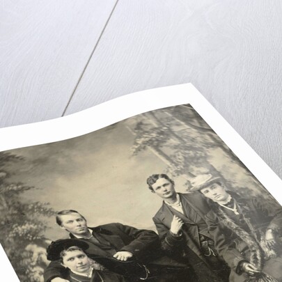 Two men and two women standing and sitting in front of a painted backdrop (forest) by Anonymous
