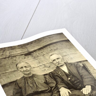 Portrait of an elderly man and woman sitting on a wooden wall or fence by Anonymous