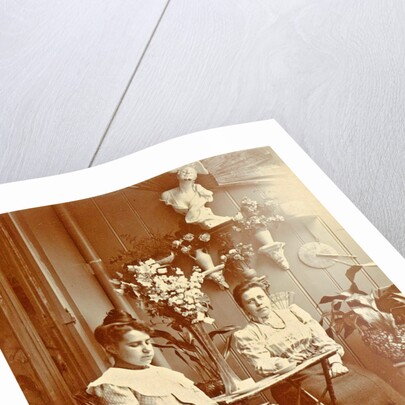 Two women sitting in a greenhouse, one reading by Anonymous