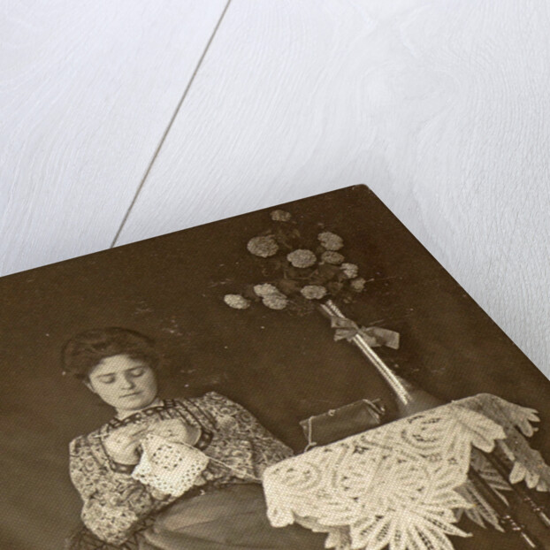 Female working at a table with tablecloth and flowers by Anonymous