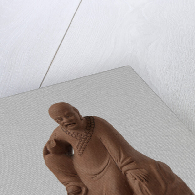 Man figure with raised right leg on rocky pedestal. Red stoneware. by Anonymous