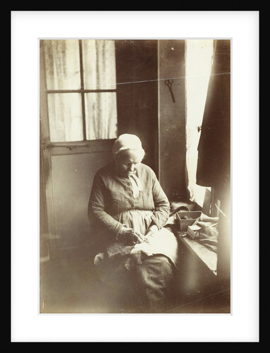 Old woman sitting by a window sewing by Anonymous