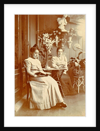 Two women sitting in a greenhouse, one reading by Anonymous