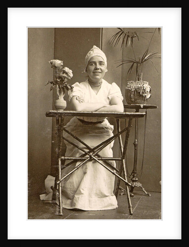 Woman with a maid's cap on, sitting at a table with flowers by Anonymous