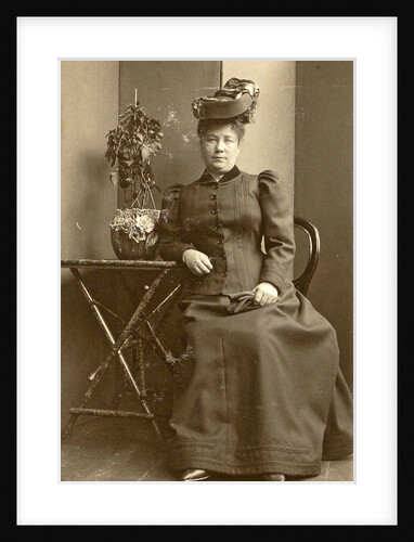 Woman with a hat, sitting next to a table with a plant by Anonymous