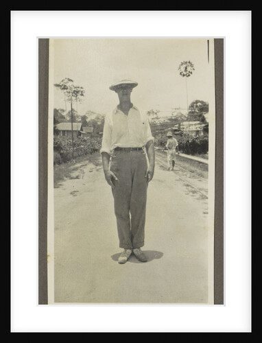 Man wearing a pith helmet posing on a road by Anonymous