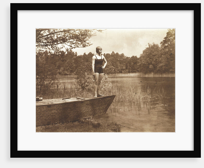 Unidentified young woman in swimsuit on a rowing boat standing on the edge of a lake by Waldemar Titzenthaler