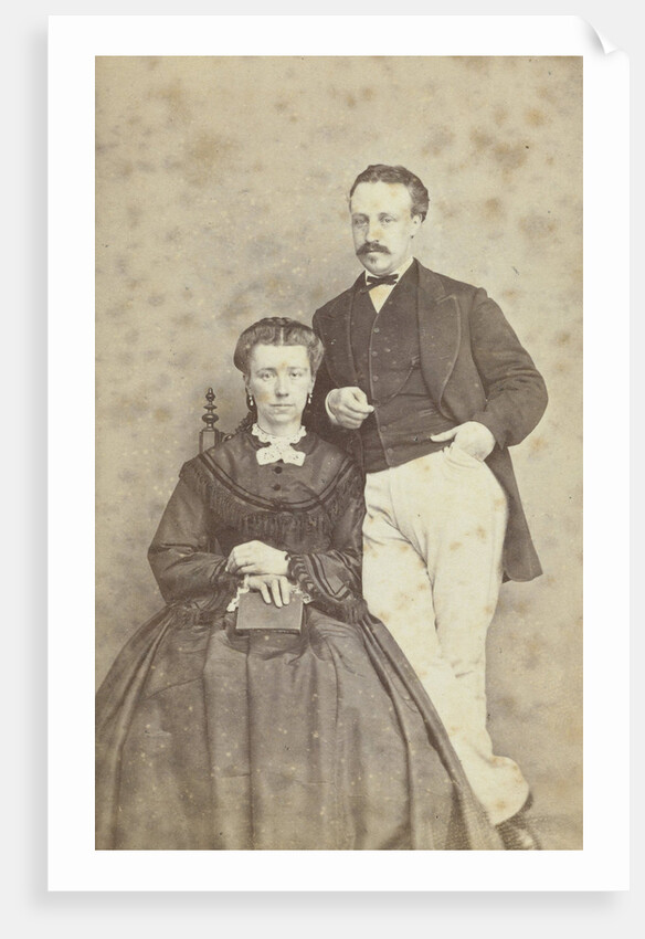 A seated woman with a book in her hands, leaning on her chair, a man in white trousers, one hand in his pocket by F.D. van Rosmalen & Zoon