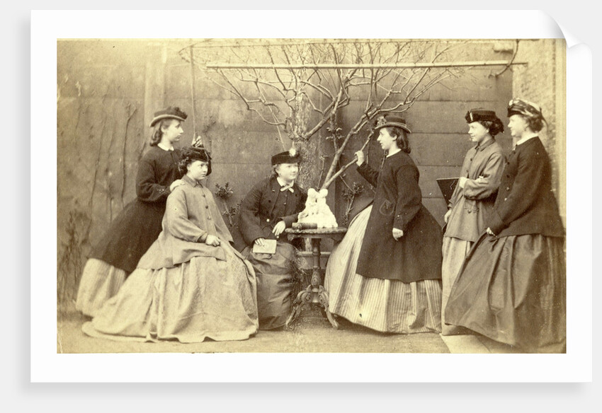 Group portrait of six young women in garden round table with sculpture, hats and coats by L. de Koningh